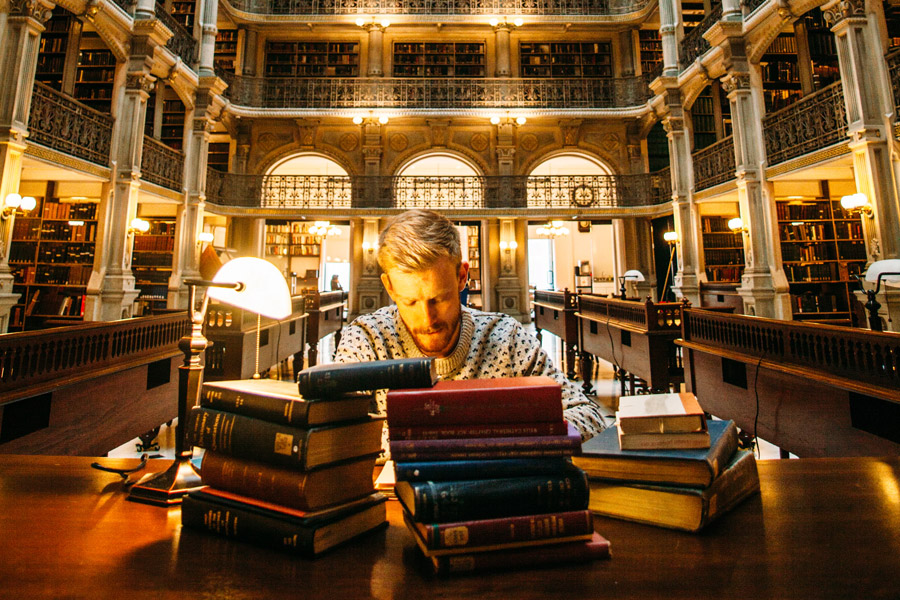 Man in a library studying with a pile of books